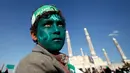 Seorang remaja dengan wajah yang dicat hijau dan bertuliskan kalam Allah, mengikuti peringatan hari kelahiran Nabi Muhammad di Sanaa, Yaman (11/12). (Reuters/Khaled Abdullah)