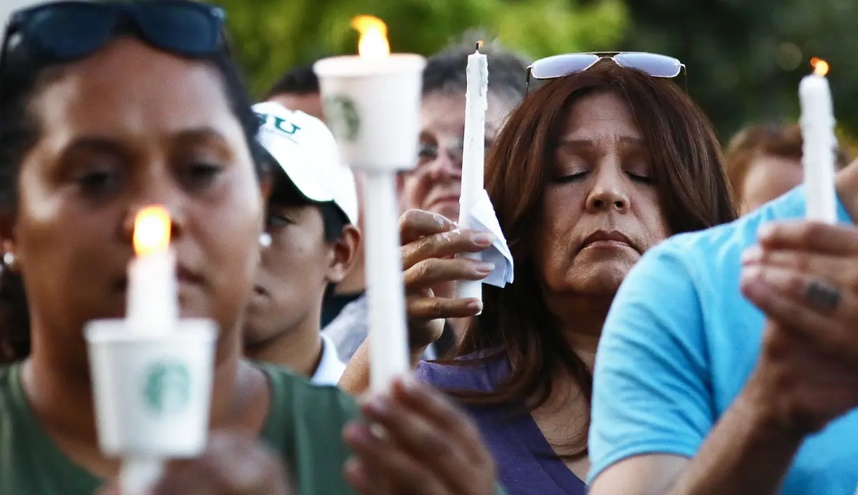 Seorang wanita berdoa sambil memegang lilin  saat menghadiri acara untuk korban penembakan brutal di festival kuliner Gilroy Garlic di Gilroy, California (29/7/2019). Tiga orang tewas dan sedikitnya puluhan orang terluka akibat kejadian tersebut. (AFP Photo/Mario Tama)