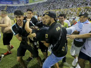 Tragedi sepak bola yang melibatkan suporter kembali terjadi. Kali ini 12 orang dilaporkan meninggal dunia dalam sebuah insiden tragis di Stadion Monumental, Cuscatlan, San Salvador, El Salvador, Sabtu (21/5/2023) malam waktu setempat pada laga perempatfinal Divisi Utama El Salvador antara Alianza FC menghadapi Deportivo FAS. Para korban tewas akibat berdesakan saat menyerbu salah satu pintu masuk stadion. Akibat kejadian tersebut, laga pun terpaksa dihentikan setelah terjadi desak-desakan suporter yang meluber hingga ke dalam lapangan. (AP Photo/Milton Flores)