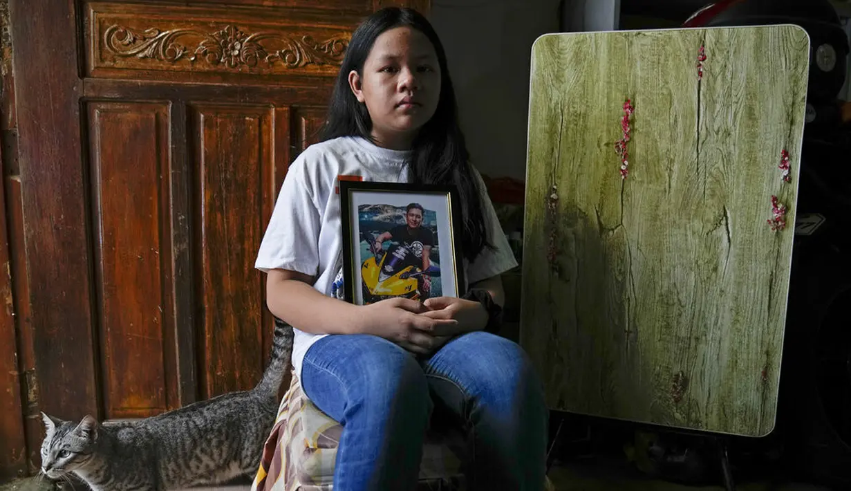 Yael Navales berpose di rumahnya dengan gambar ayahnya, Arthur, yang meninggal karena virus corona di kota Quezon, Filipina, pada 6 Juli 2021. "Rumah kami menjadi sunyi dan sedih. Kami tidak banyak tertawa sejak papa pergi," katanya. (AP Photo/Aaron Favila)