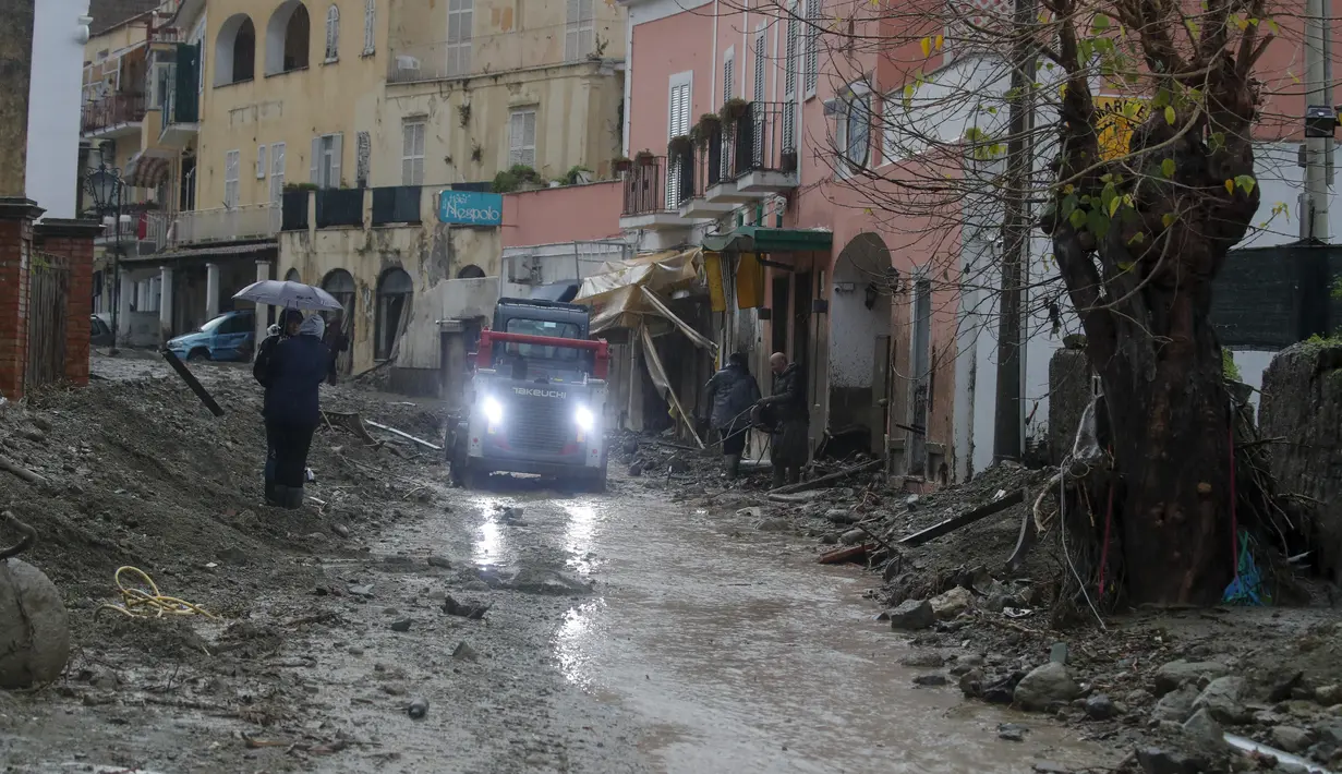 Sebuah mobil mengeluarkan lumpur dari jalan yang banjir setelah hujan deras memicu tanah longsor yang meruntuhkan bangunan dan menyebabkan 12 orang hilang, di Casamicciola, di pulau Ischia, Italia selatan, Sabtu, 26 November 2022. (AP Photo/Salvatore Laporta)