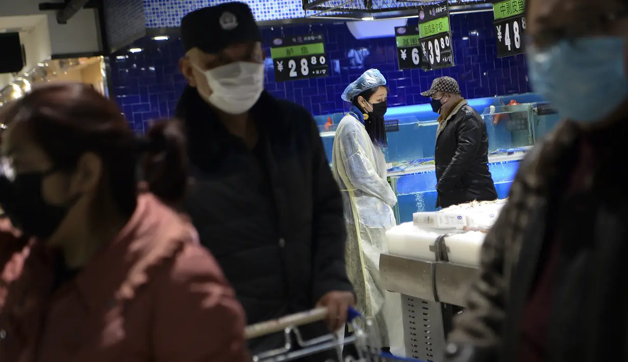 Seorang wanita mengenakan jas hujan dan masker berada di sebuah supermarket di Wuhan, provinsi Hubei, China, Senin, (10/2/2020). Angka kematian akibat virus corona di China meningkat lagi, dengan kematian hari Senin (10/2/2020) mencapai 908 orang, dengan adanya 97 kematian baru. (Chinatopix via AP)