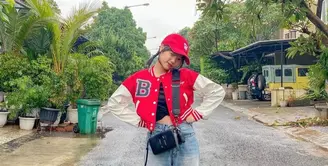 Boyfriend jeans dan crop baseball jacket berwarna merah putih bisa menjadi pilihan. Semakin kece dengan tambahan topi dan sling bag seperti adik ipar mendiang Vanessa Angel, Fuji. (Instagram/fuji_an).