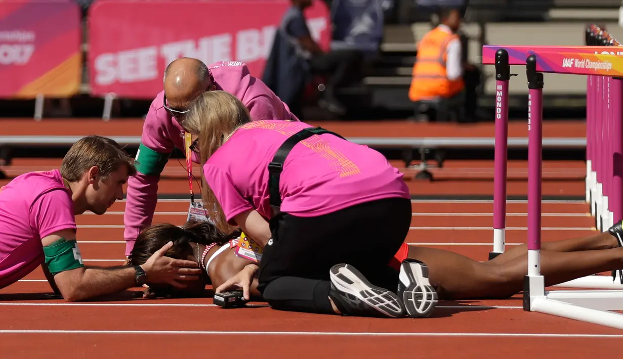 Petugas medis memberikan pertolongan kepada atlet Trinidad dan Tobago, Deborah John yang cedera usai terjatuh dalam cabang lari halang rintang 100 meter putri Kejuaraan Atletik Dunia di Stadion London, Inggris (11/8). (AP Photo/Matt Dunham)