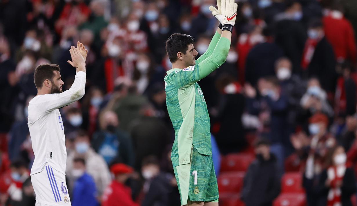 Kiper Real Madrid, Thibaut Courtois (kanan) menyapa pendukungnya usai pertandingan melawan Athletic Bilbao pada pertandingan La Liga Spanyol di stadion San Mames, Spanyol, Kamis (23/12/2021). Madrid menang atas Bilbao 2-1. (AP Photo/Ricardo Larreina)