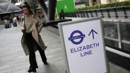 Seorang penumpang berjalan melewati tanda di Stasiun Canary Wharf Elizabeth Line yang baru dibuka di London Timur, Inggris, Senin (7/11/2022). Elizabeth Line baru saja melakukan layanan penuh gabungan untuk pertaman kalinya. (Daniel LEAL / AFP)