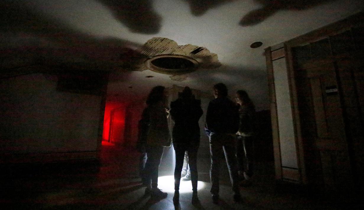 Pengunjung mendengarkan instruksi saat berada didalam rumah hantu Quinta Nova da Assuncao di Belas, Portugal (13/5). Pengunjung akan diajak tur di dalam rumah kosong Quinta Nova da Assuncao. (REUTERS/Rafael Marchante)