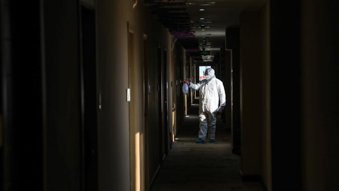 Pekerja berpakaian pelindung menyemprotkan desinfektan pada lorong hotel yang digunakan dalam isolasi medis virus corona di Wuhan, Provinsi Hubei, China, Senin (3/2/2020). Pengungkap virus corona, dr Li Wenliang, meninggal pada 7 Februari 2020 akibat virus corona. (Chinatopix via AP)