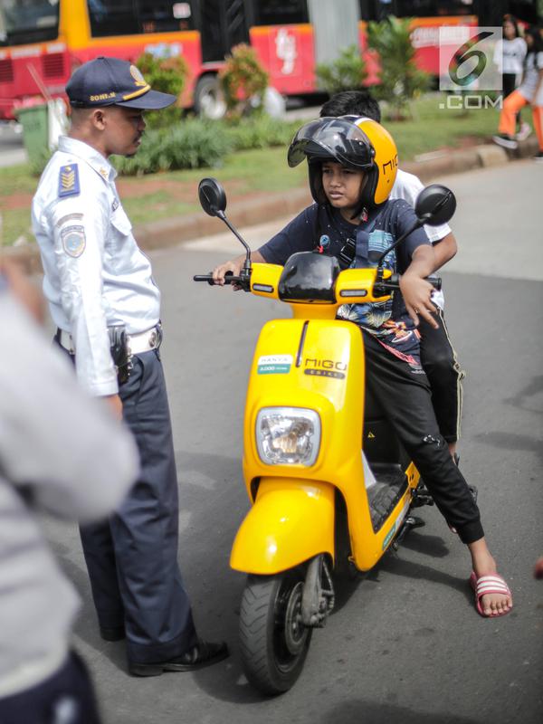 Petugas Dishub mensosialisasikan kepada pengendara sepeda motor listrik Migo saat melintasi CFD di kawasan Bundaran HI, Jakarta, Minggu (17/2). Penyewa sepeda motor listrik dihimbau untuk tidak melintasi jalan raya. (Liputan6.com/Faizal Fanani)
