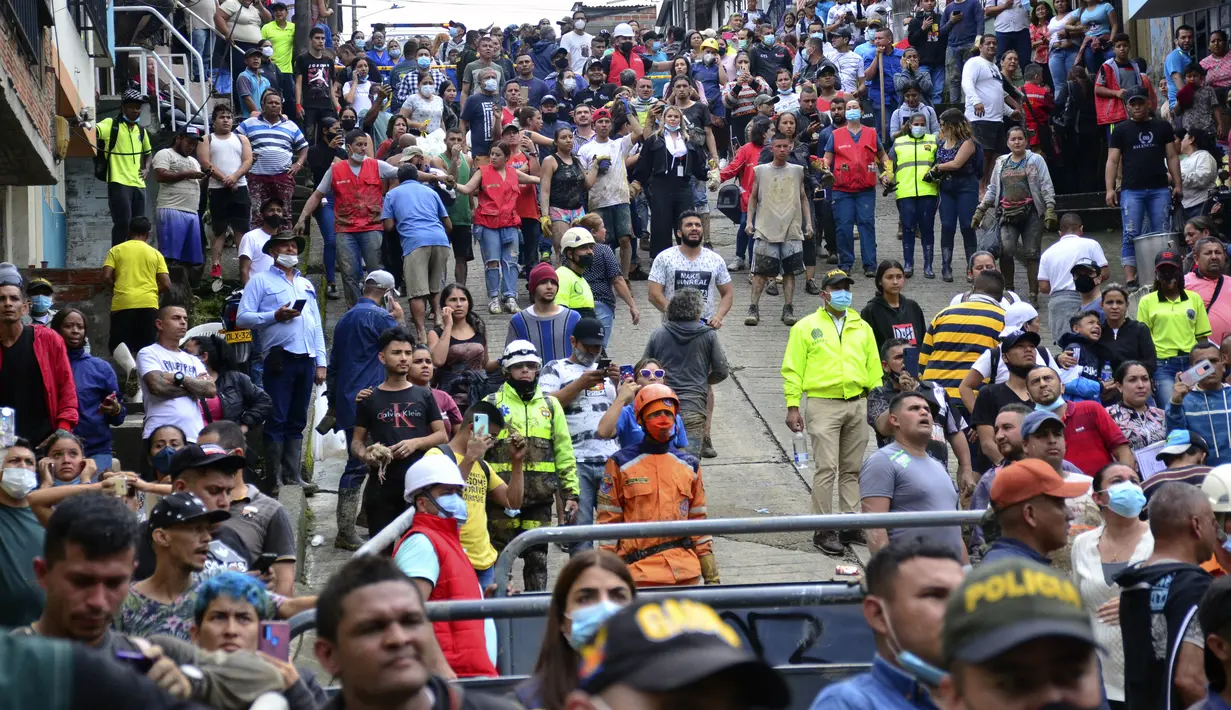 Warga yang dievakuasi menyaksikan operasi penyelamatan setelah lereng bukit runtuh menimpa rumah mereka di Pereira, Kolombia, Selasa (8/2/2022). Hujan deras memicu tanah longsor yang melanda kawasan perumahan ini, menewaskan sedikitnya 14 orang dan melukai 35 lainnya. (AP Photo/Andres Otalvaro)