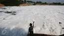 Seorang anak memancing di permukaan air yang tertutupi busa berwarna putih di Pintu Air Marunda Hilir, Jakarta, Selasa (17/5). Pencemaran air tersebut disebabkan pembuangan limbah rumah tangga dan industri secara langsung. (Liputan6.com/Immanuel Antonius)