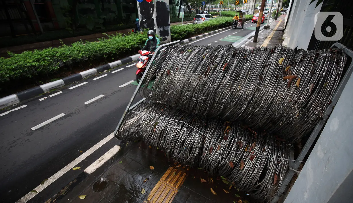 Pengendara melintas dekat kawat berduri yang diletakkan di atas trotoar Jalan Asia Afrika, Jakarta Pusat, Selasa (28/12/2021). Kawat berduri yang berada di trotoar tersebut sangat mengganggu para pejalan kaki yang melintas. (Liputan6.com/Johan Tallo)