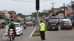 Petugas polisi berjaga di pertigaan Jatinangor, Sumedang, Jawa Barat, Sabtu (2/7). Mengatasi kepadatan kendaraan pemudik, petugas melakukan sistem pengalihan arus dengan menutup jalur dari arah Sumedang menuju Bandung Kota (Liputan6.com/Immanuel Antonius)