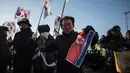 Pengunjuk rasa anti-Korea Utara merobek bendera Korea Utara saat melakukan aksi menyambut kedatangan kapal feri Korea Utara yang membawa rombongannya untuk Olimpiade Musim Dingin Pyeongchang 2018, Korea Selatan (6/2). (AFP/Ed Jones)