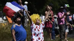 Aksi suporter memegang bendera Prancis saat menonton balapan  Tour de France pada etape ke-16 dengan jarak 165 km dari Le Puy-en-Velay dan Romans-sur-Isere, (18/7/2017).  (AFP/Jeff Pachoud)