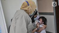 Dokter menenangkan balita usai diberikan imunisasi di Puskesmas Kecamatan Jatinegara, Jakarta, Kamis (26/11/2020). (merdeka.com/Iqbal S. Nugroho)