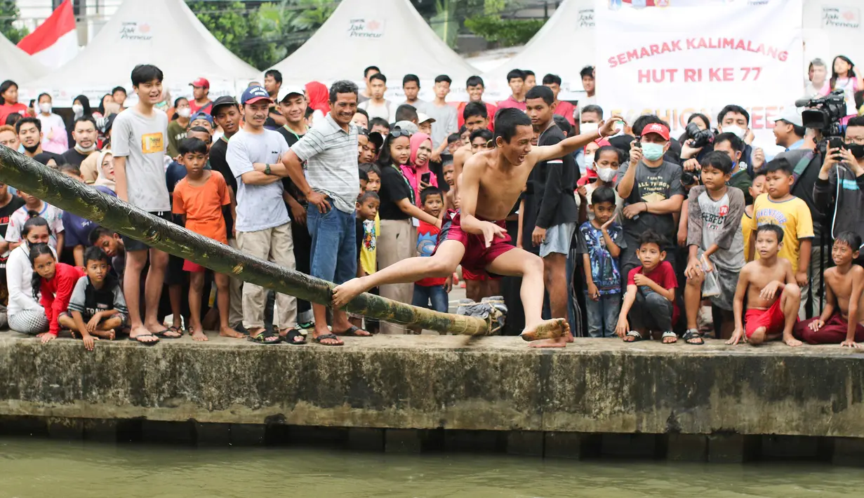 Seorang warga terjatuh saat mengikuti perlombaan jalan di atas bambu di aliran Kalimalang, Jakarta Timur, Sabtu (27/8/2022). Perlombaan di Kalimalang yang diselenggarakan kembali setelah dua tahun berhenti akibat pandemi covid-19 ini untuk memeriahkan peringatan HUT ke-77 Kemerdekaan RI. (Liputan6.com/Herman Zakharia)