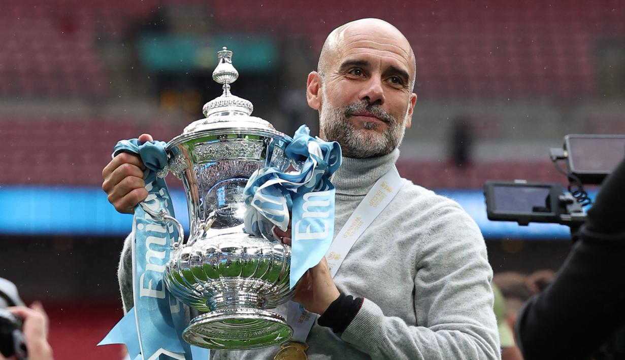 Pelatih Manchester City, Pep Guardiola berfoto dengan Piala FA setelah mengalahkan Chelsea dengan skor 1-0 di partai final di Wembley Stadium hari Sabtu (16/05/2026) malam WIB. (AFP/Adrian Dennis)