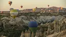 Balon udara membawa wisatawan naik ke langit saat matahari terbit di Kapadokia, Turki, Selasa (7/8). Cerobong Peri Kapadokia adalah lansekap batu vulkanik berbentuk kerucut yang menjulang tinggi ke langit. (AP Photo/Emrah Gurel)