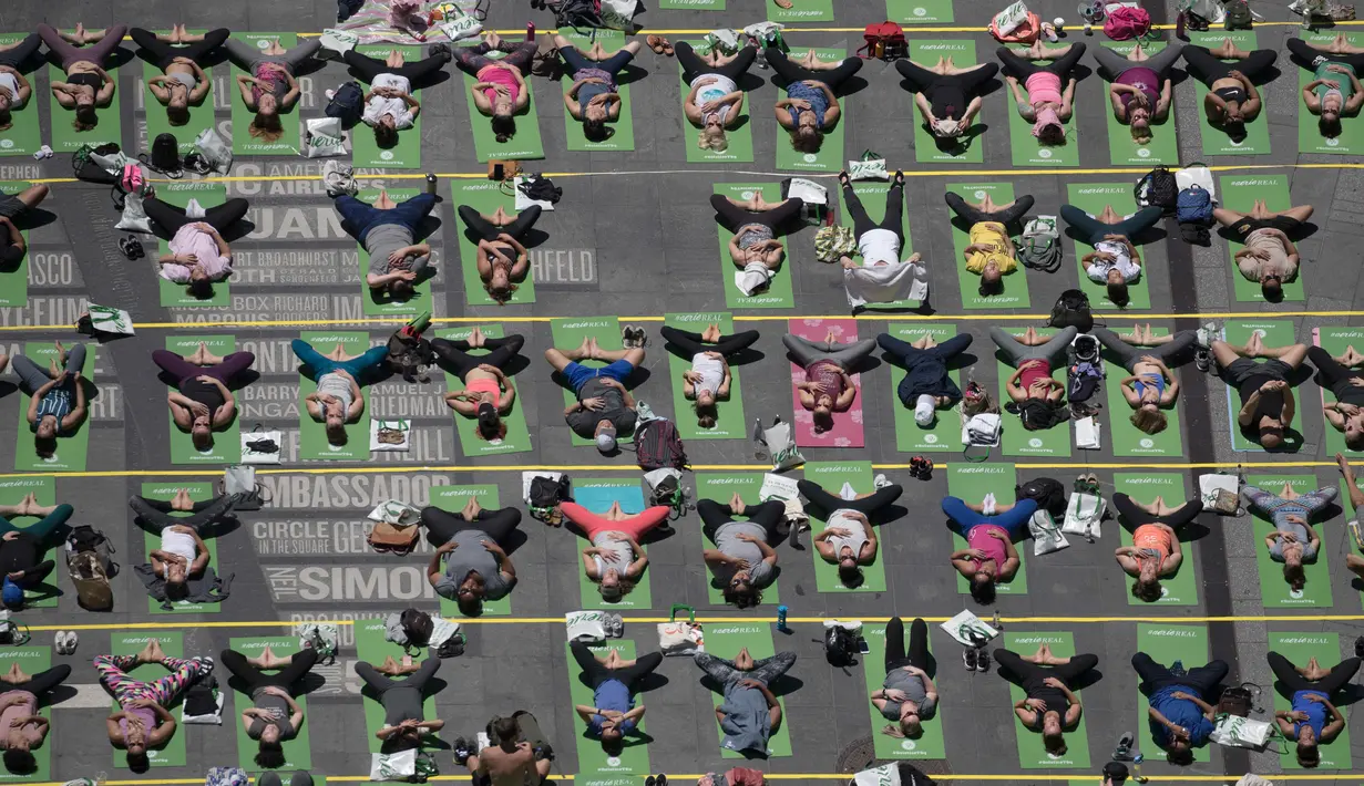 Sejumlah orang melakukan gerakan yoga saat matahari mencapai titik balik di musim panas (summer solstice) di kawasan Times Square, New York, Kamis (21/6). Ribuan orang berkumpul untuk merayakan titik balik matahari di musim panas. (AP Photo/Mary Altaffer)