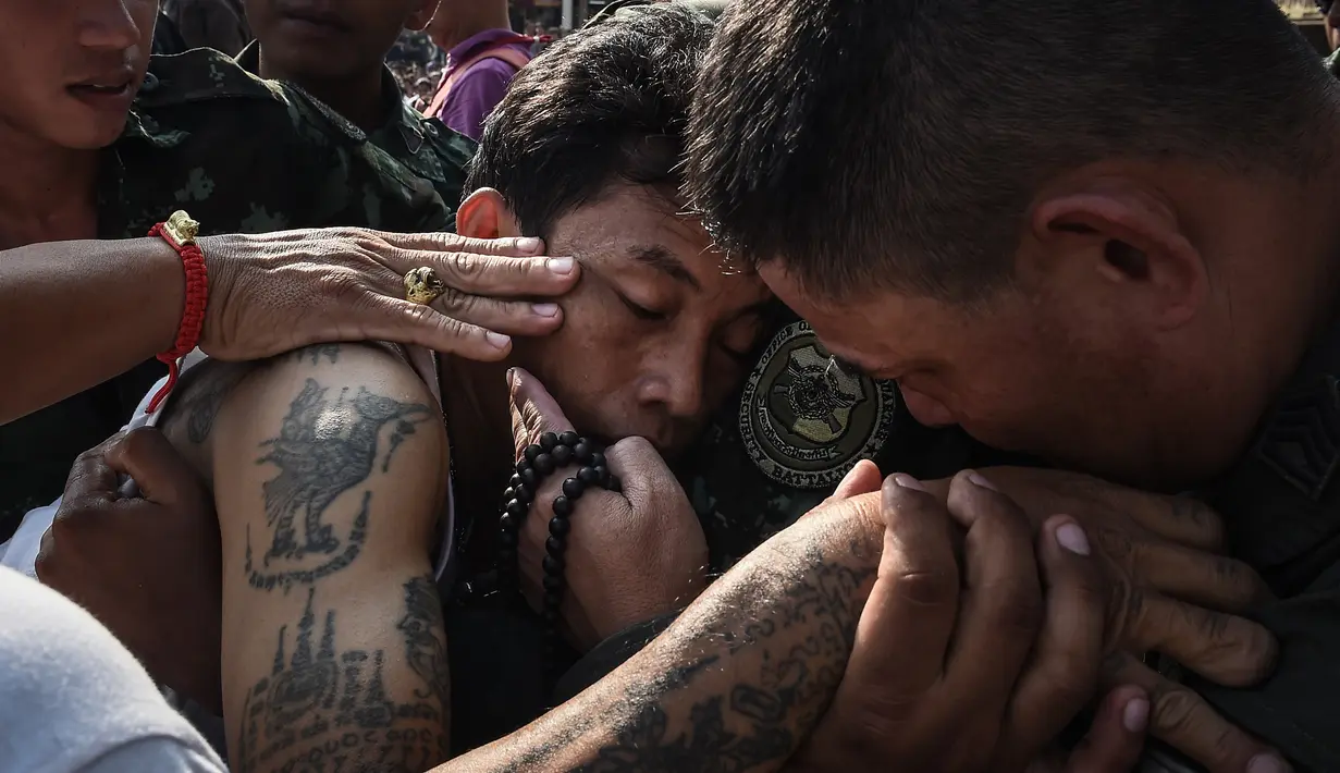 Petugas kemananan setempat menangani pria yang kesurupan saat mengikuti festival tato suci di Biara Wat Bang Phra, Nakhon Pathom, Thailand (3/3). Sebagian orang percaya bahwa tato ini dapat menangkal kerusakan fisik. (AFP Photo/Lillian Suwanrumpha)
