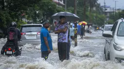 Warga berdiri di jalan yang tergenang air saat hujan deras di Guwahati, negara bagian Assam, India, Kamis (16/6/2022). Guwahati telah menerima curah hujan 81,5 mm dalam 24 jam terakhir yang termasuk dalam kategori 'hujan lebat' dalam 24 jam terakhir. (AP Photo/Anupam Nath)
