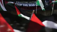 Bendera Palestina dikibarkan di depan spanduk saat orang-orang berkumpul dalam unjuk rasa pro-Palestina di Sydney, Sabtu, 21 Oktober 2023. (AP Photo/Rick Rycroft)