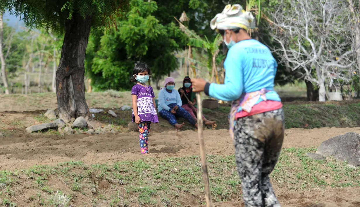 Warga mengenakan masker saat beraktivitas di kecamatan Kubu, Kabupaten Karangasem, Bali (27/11). Dampak hujan abu dari Gunung Agung menyebabkan warga harus menggunakan masker. (AFP/Sonny Tumbelaka)