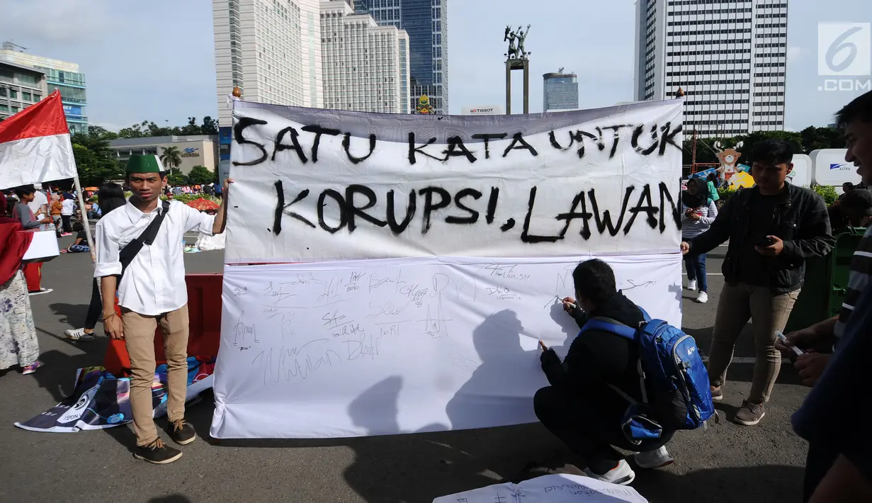 Warga menandatangani spanduk dukungan antikorupsi yang dibentangkan saat Hari Bebas Kendaraan di kawasan Bundaran HI, Jakarta, Minggu (10/12). Aksi dilakukan untuk memperingati Hari Antikorupsi Sedunia, 9 Desember. (Liputan6.com/Helmi Fithriansyah)