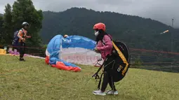 Paraglider bersiap untuk lepas landas dari lereng bukit di Puncak, Bogor, Jawa Barat, Kamis (2/12/2021). Destinasi wisata alam Bukit Paralayang Puncak Bogor sangat cocok untuk dikunjungi pada liburan akhir pekan bersama keluarga, sahabat maupun pasangan tercinta. (Goh Chai Hin/AFP)