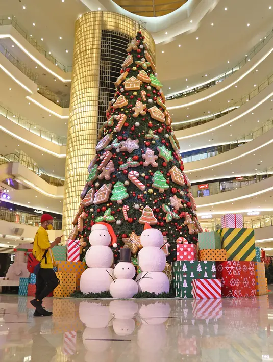 Pengunjung melintas di dekat pohon Natal di Senayan City, Jakarta, Senin (21/12/2020). Pohon Natal ini didominasi permainan warna hijau, merah, putih dan emas dan sekeliling pohon Natal dengan beragam wrapping gift boxes warna-warni berukuran besar. (Liputan6.com/Herman Zakharia)