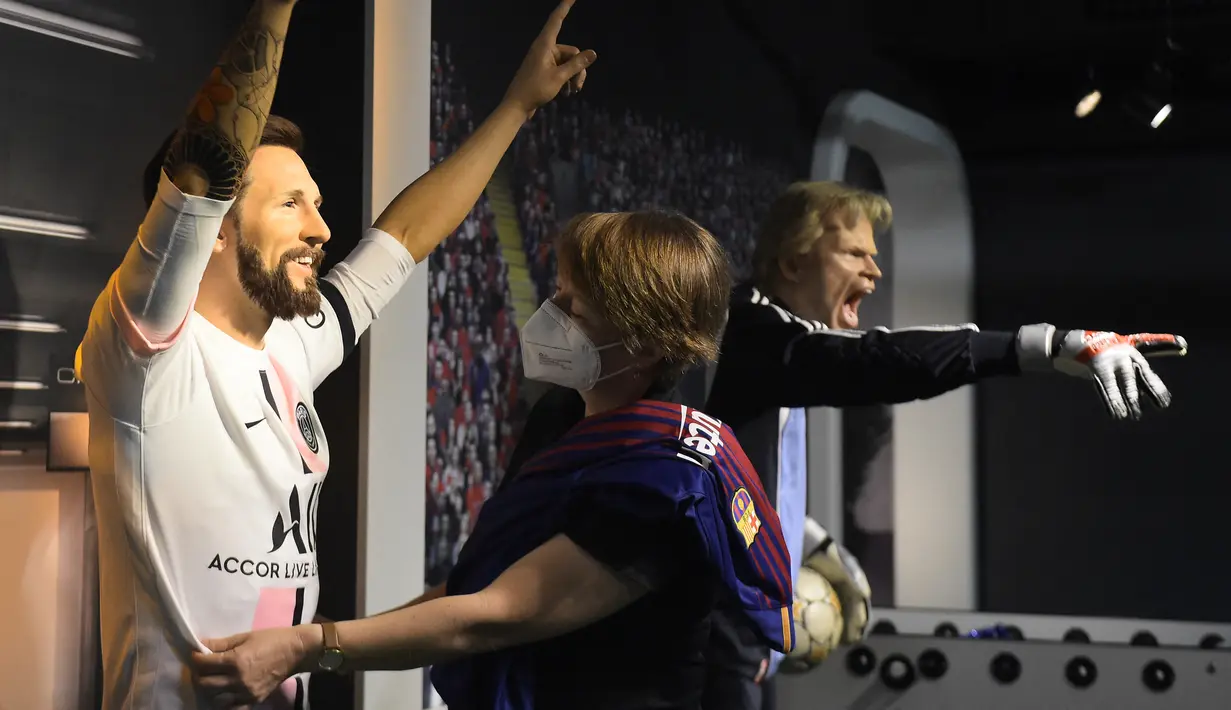 Seorang tim potret museum lilin Madame Tussauds Berlin, Karen Fries (kanan) memperbaiki jersey baru Paris Saint-Germain (PSG) pada patung lilin Lionel Messi di Berlin. (11/7/2021). (AFP/Tobias Schwarz)