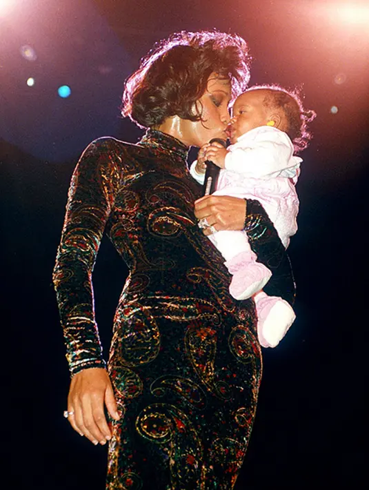 Whitney Houston bersama Kristina kecil di atas panggung. (via People.com)