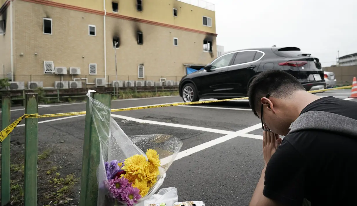 Seorang pria berdoa untuk para korban setelah meletakkan bunga di luar gedung Kyoto Animation Studio di Kyoto, Jepang (19/7/2019).Stasiun televisi NHK melapor, seorang pria yang menuangkan bensin ke sekitar gedung animasi telah ditahan. (AP Photo/Jae C. Hong)