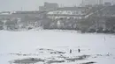 Orang-orang berjalan di dekat danau Qargha saat hujan salju di Kabul (4/1/2022). Sedikitnya tujuh warga Afghanistan tewas dan 26 lainnya cedera dalam beberapa kecelakaan lalu lintas. (AFP/Mohd Rasfan)