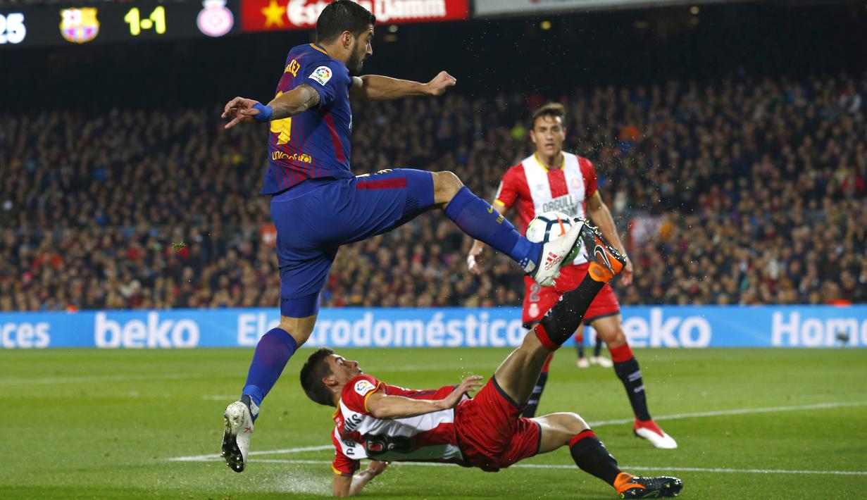 Aksi pemain FC Barcelona, Luis Suarez melepaskan tembakan saat diadang pemain Girona pada La Liga Santander di Camp Nou stadium, Barcelona, (24/2/2018). Barcelona menang telak 6-1. (AP/Manu Fernandez)