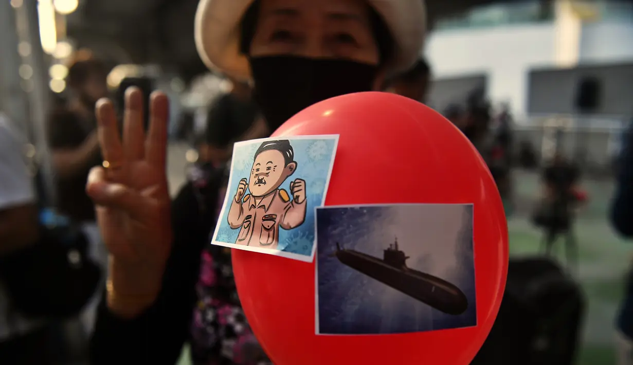 Seorang pengunjuk rasa memegang balon sambil memberi hormat pada Hunger Games dengan tiga jari selama demonstrasi menentang pembelian kapal selam oleh pemerintah yang berpihak pada militer di Bangkok (31/8/2020). (AFP/Lillian Suwanrumpha)