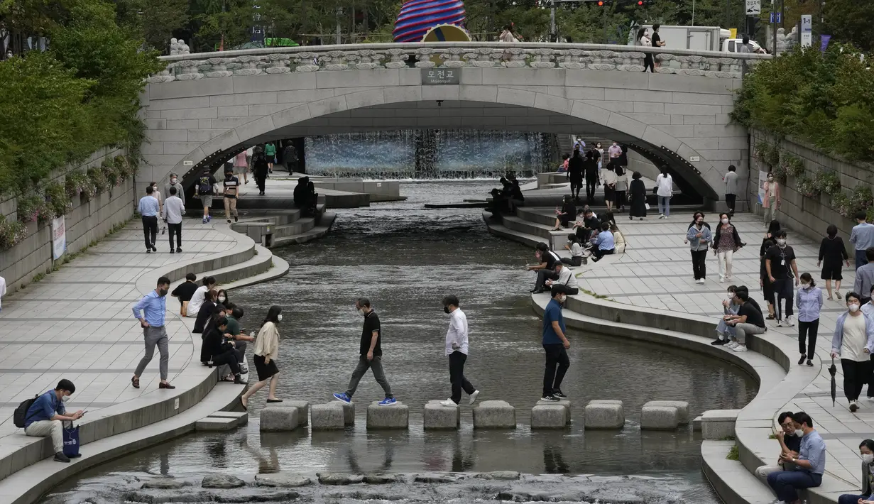Orang-orang menyeberangi sungai Cheonggye di Seoul, Korea Selatan, Rabu (1/9/2021). Rekor harian kasus virus corona yang ditetapkan bulan lalu hanya sehari setelah para pejabat dengan hati-hati menyatakan harapan bahwa infeksi mungkin lambat. (AP Photo/Ahn Young-joon)