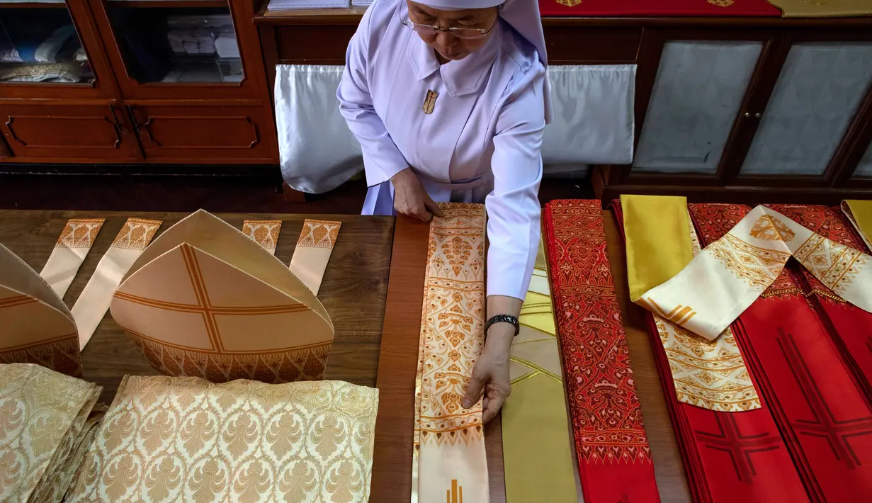 Suster Sukanya Sukchai merapikan pakaian upacara yang akan digunakan Paus Fransiskus saat mengunjungi Thailand, Bangkok, Jumat (8/11/2019). Jika jubah Paus Fransiskus terbuat dari sutra, para uskup nantinya mengenakan jubah berbahan poliester. (AP Photo/Gemunu Amarasinghe)
