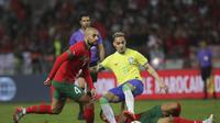 Gelandang Maroko, Sofyan Amrabat, berduel melawan pemain Brasil, Antony dalam laga uji coba di Grand Stade de Tanger, Tangier, Minggu (26/3/2023) pagi WIB. (AP/Mosha'ab Elshamy)