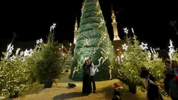 Warga berfoto dengan latar belakang pohon Natal yang dirancang oleh desainer Lebanon, Elie Saab di depan Masjid Al-Amin, di pusat kota Beirut, 12 Desember 2015. (REUTERS/Jamal Saidi)