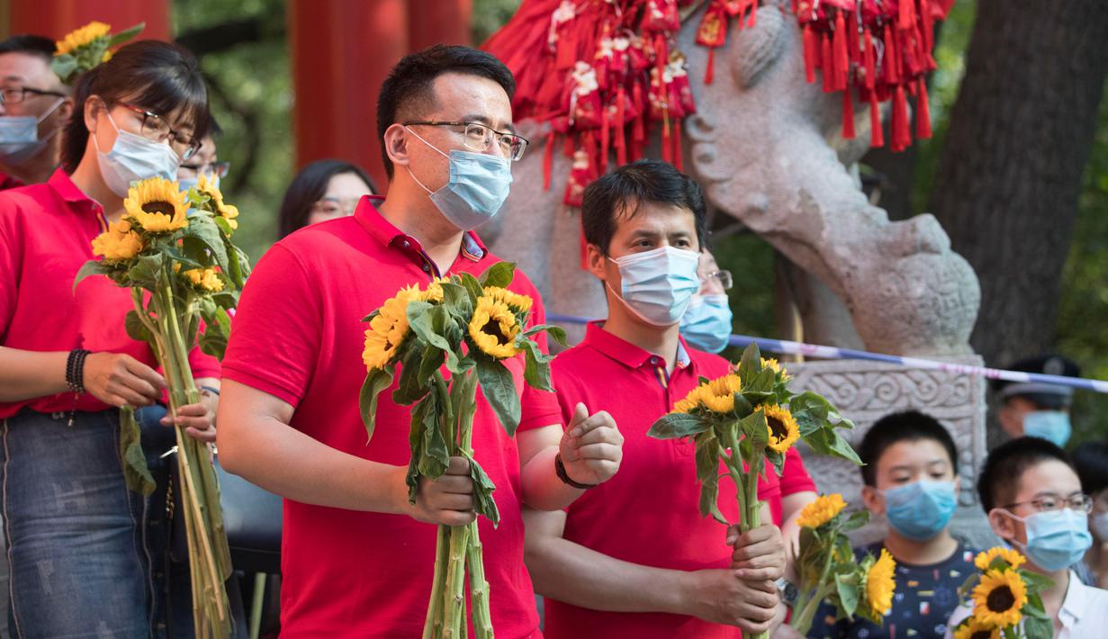 Para guru yang memegang bunga matahari menunggu para peserta di luar lokasi ujian masuk perguruan tinggi di Kota Harbin, Provinsi Heilongjiang, China, pada 8 Juli 2020. Ujian masuk perguruan tinggi nasional telah selesai digelar di beberapa bagian wilayah China pada Rabu (8/7). (Xinhua/Zhang Tao)