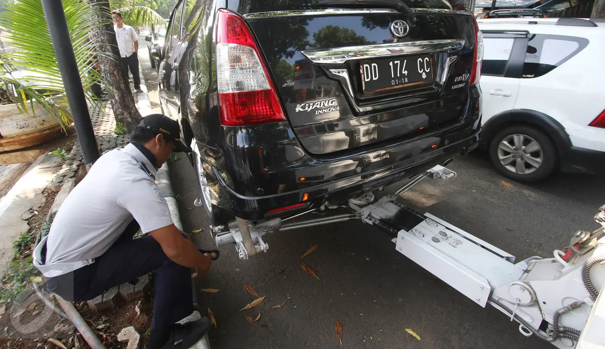Petugas Dishub memasang alat derek ke kendaraan yang parkir liar di kawasan Pasar Baru, Jakarta, Kamis (7/1). Pemprov DKI berencana menaikan denda Rp 3 juta per hari terhadap kendaraan yang terjaring parkir liar. (Liputan6.com/Immanuel Antonius)
