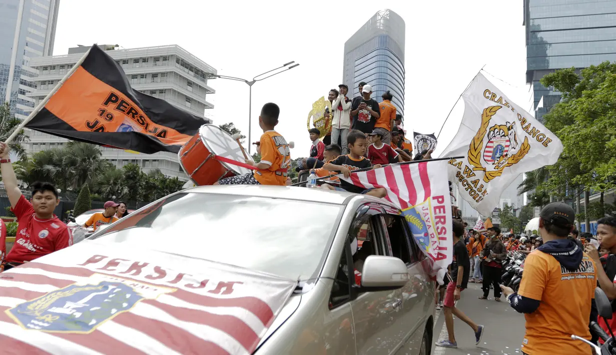 Suporter Persija Jakarta, The Jakmania, konvoi merayakan gelar Piala Liga 1 musim 2018 di Bundaran HI, Jakarta, Sabtu (15/12). Persija berhasil juara Liga 1 usai mengalahkan Mitra Kukar. (Bola.com/Yoppy Renato)