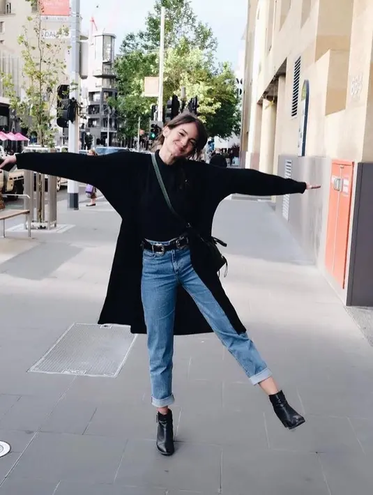Bisa jadi inspirasi outfit liburan, padukan long coat warna hitam dengan turtleneck top dan boyfriend jeans. (Instagram/enzystoria)