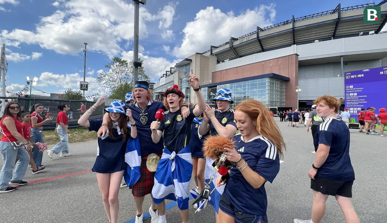 Suporter Skotlandia atau Tartan Army bernyanyi dan meneriakkan yel-yel di area fanzone Gillette Stadium, Foxborough, Amerika Serikat, Jumat (19/6/2026), menjelang laga melawan Maroko pada Piala Dunia 2026. Mereka mengenakan kilt tradisional, membawa bendera Saltire, serta berbagai atribut khas Skotlandia. (KLY Sports/Hery Kurniawan)