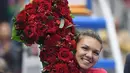 Petenis Rumania, Simona Halep memeluk buket bunga berbentuk angka satu saat merayakan kemenangan atas Jelena Ostapenko (Latvia) pada semifinal China Terbuka 2017 di Beijing, Sabtu (7/1). Halep naik ke posisi teratas WTA kali pertama. (GREG BAKER / AFP)