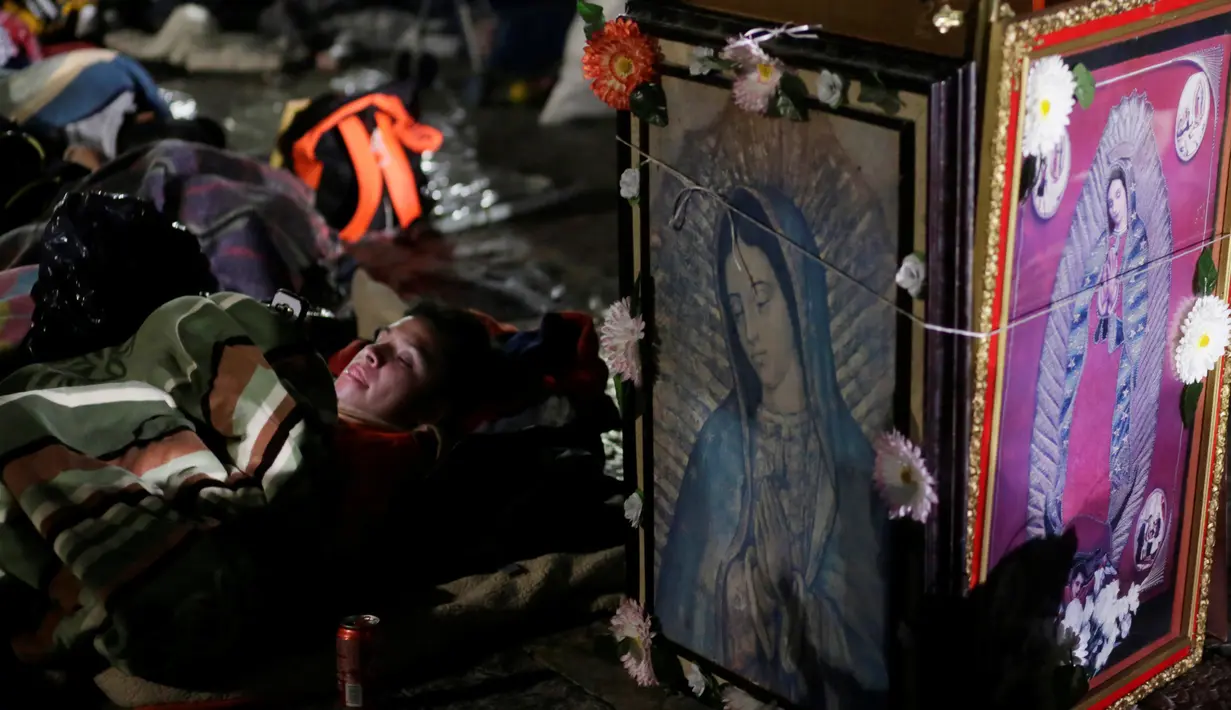 Seorang peziarah beristirahat di samping gambar Bunda dari Guadalupe di kawasan Basilika Guadalupe di Mexico City, Meksiko (11/12). Bunda dari Guadalupe dikenal juga dengan sebutan Our Lady of Guadalupe atau Virgin of Guadalupe. (Reuters/Henry Romero)