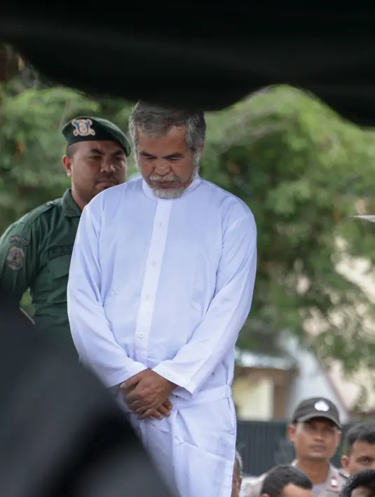 Dahlan Silitonga menjalani hukum cambuk di luar Masjid Babussalam, Banda Aceh, Aceh, Indonesia, Selasa (27/2). Dahlan bersama istrinya, Tjia Nyuk Hwa ditangkap Satpol PP dan polisi syariah saat sedang berjudi. (AFP FOTO/CHAIDEER MAHYUDDIN)