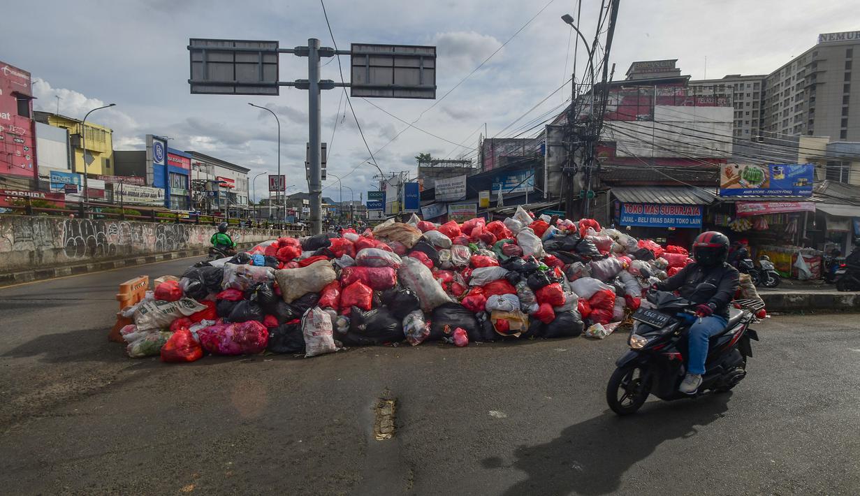 Penutupan dikarenakan adanya proses perbaikan dan penataan konstruksi timbunan sampah agar lebih aman dan tertata. Tampak dalam foto, warga dan pengendara motor melintas di dekat tumpukan sampah diletakkan pada salah sisi satu ruas jalan di kawasan Pasar Manggis, Ciputat, Tangerang Selatan, Senin (15/12/2025). (merdeka.com/Arie Basuki)